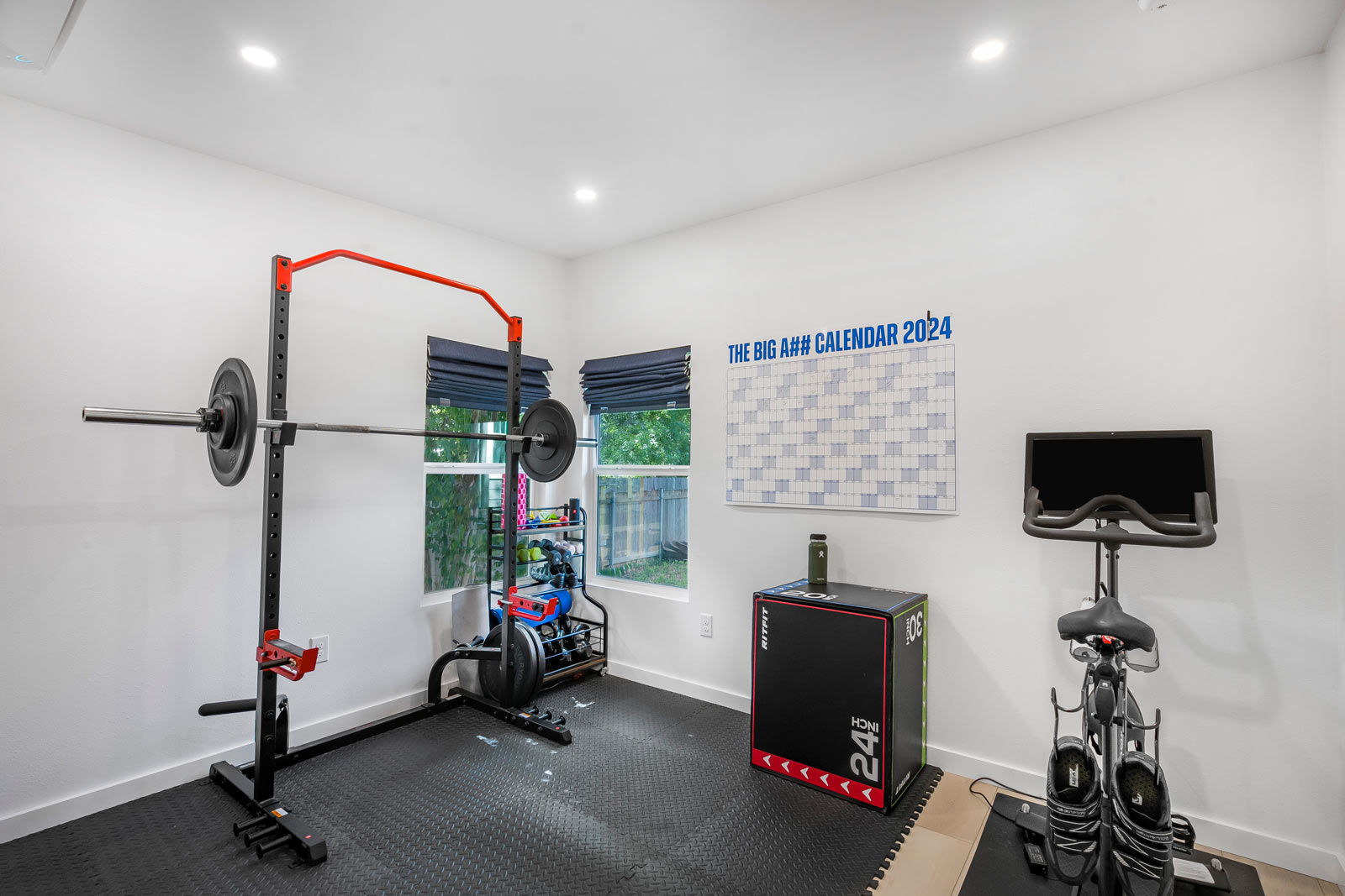 Home gym interior with squat rack, exercise bike, and rubber flooring