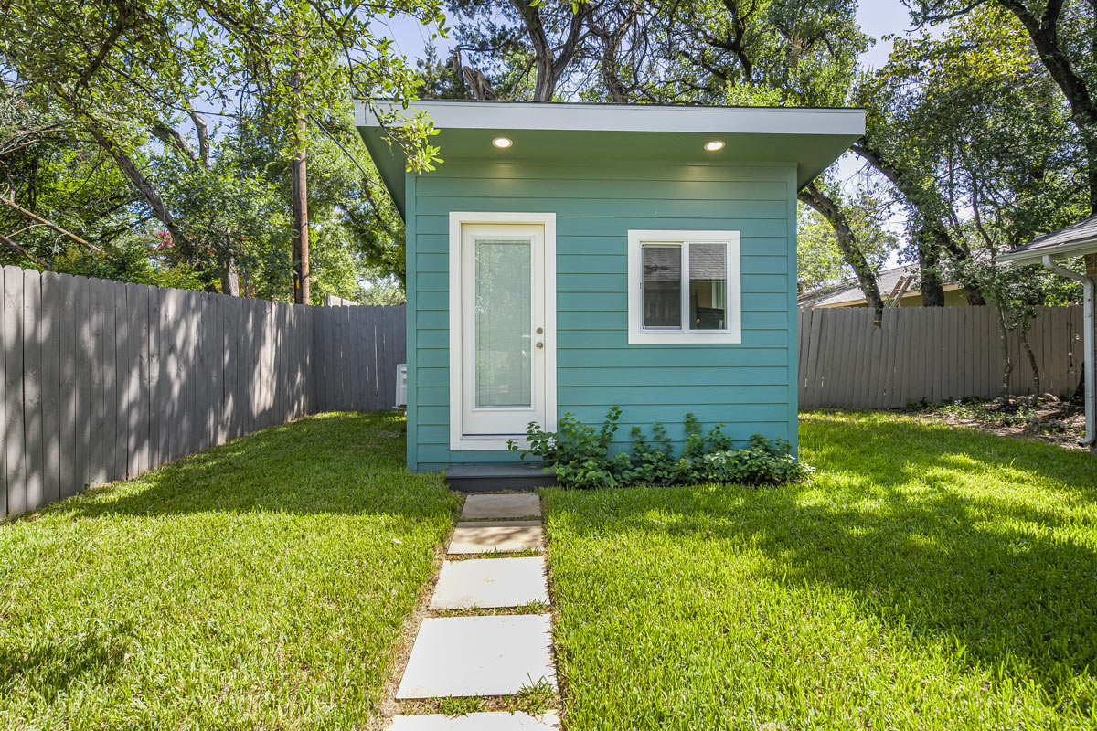 Teal backyard gym structure with mini-split and stone paver walkway