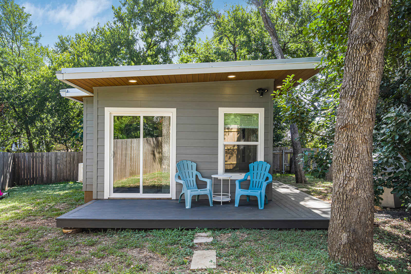 Grey-sided backyard gym with sliding glass door and deck seating